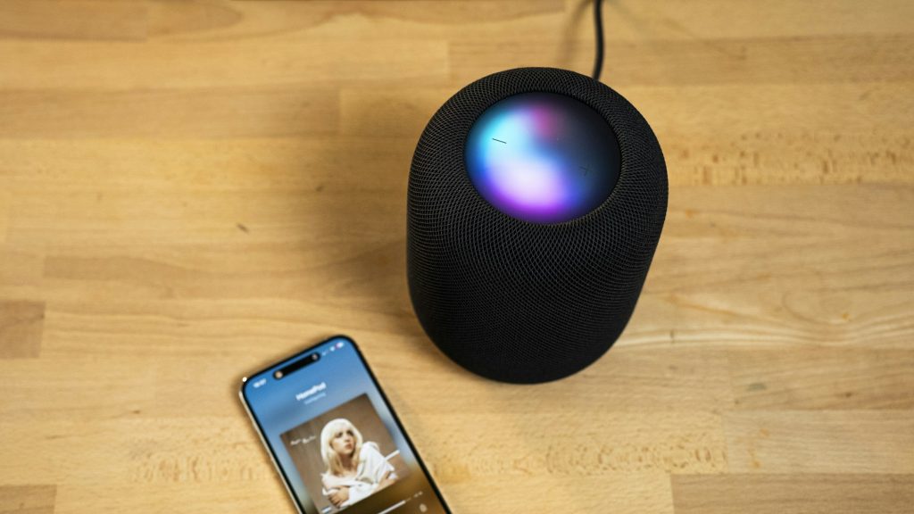 Celular junto a un altavoz inteligente para usar control por voz.