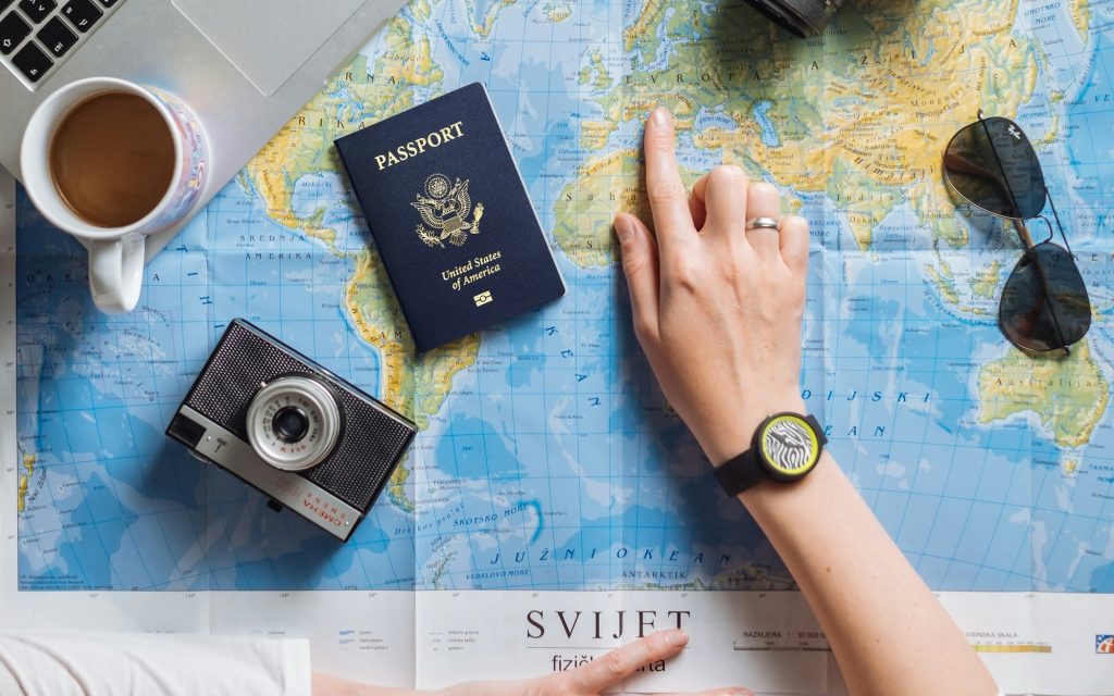Mapa, pasaporte, cámaras y computadora utilizados para planificar un viaje.